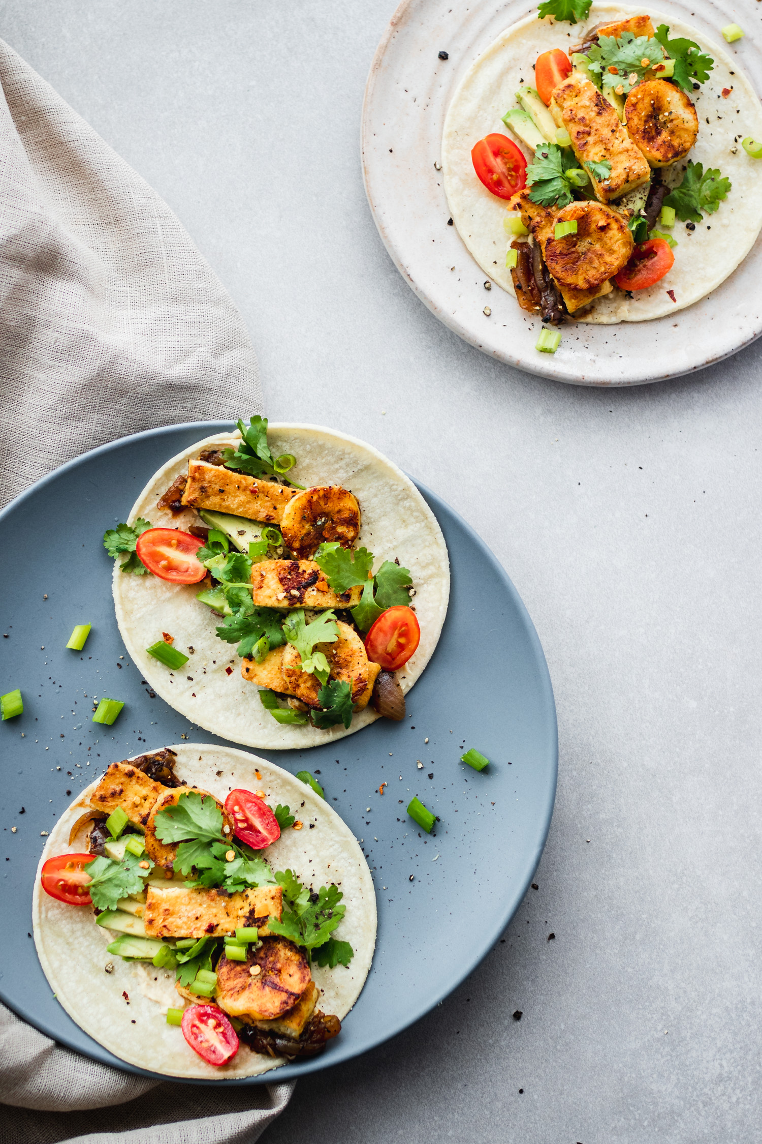 Overhead of Marinated Tofu Tacos on plate garnished with cherry tomatoes and plantains
