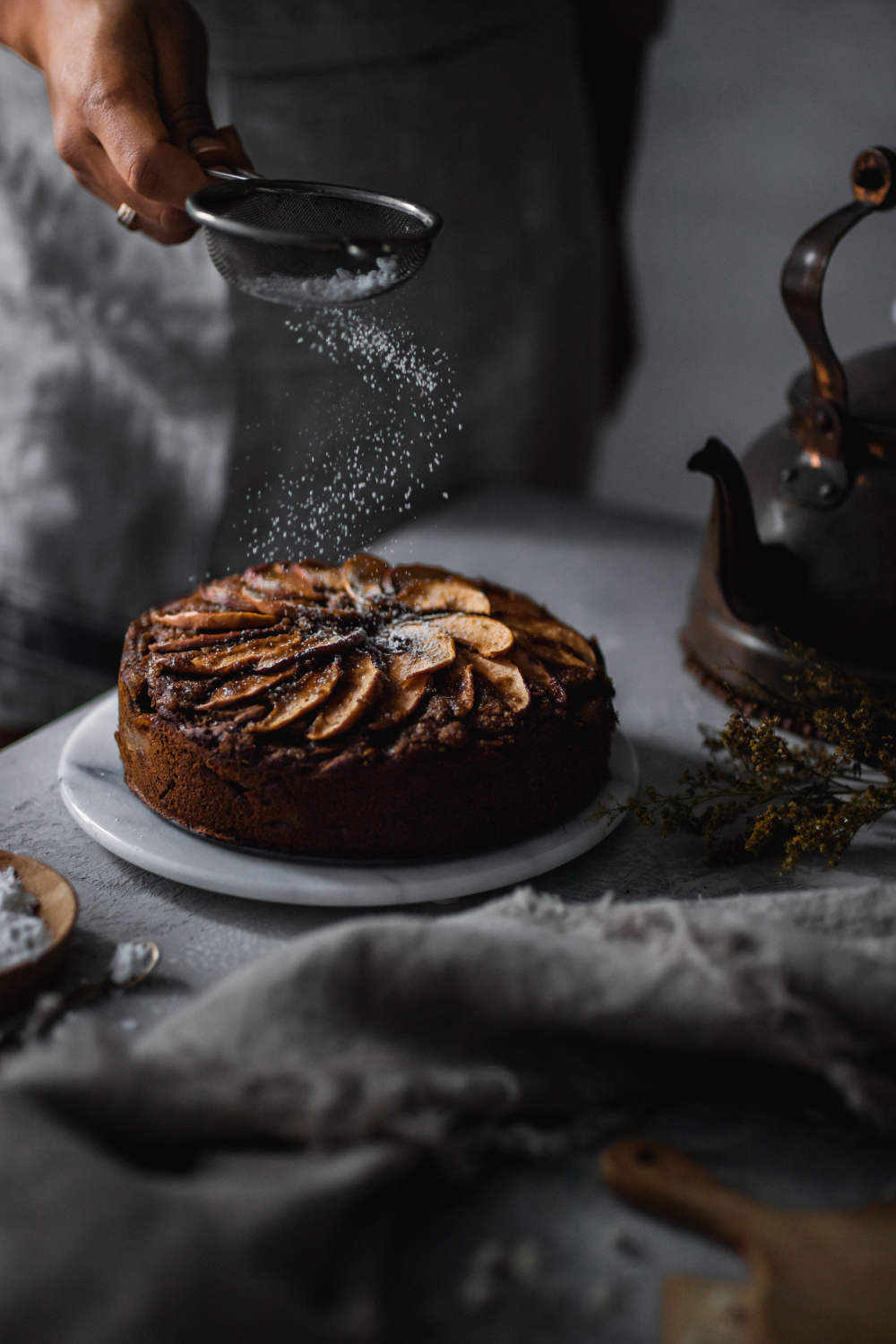 Date Sweetened Apple Cake with powdered sugar being dusted