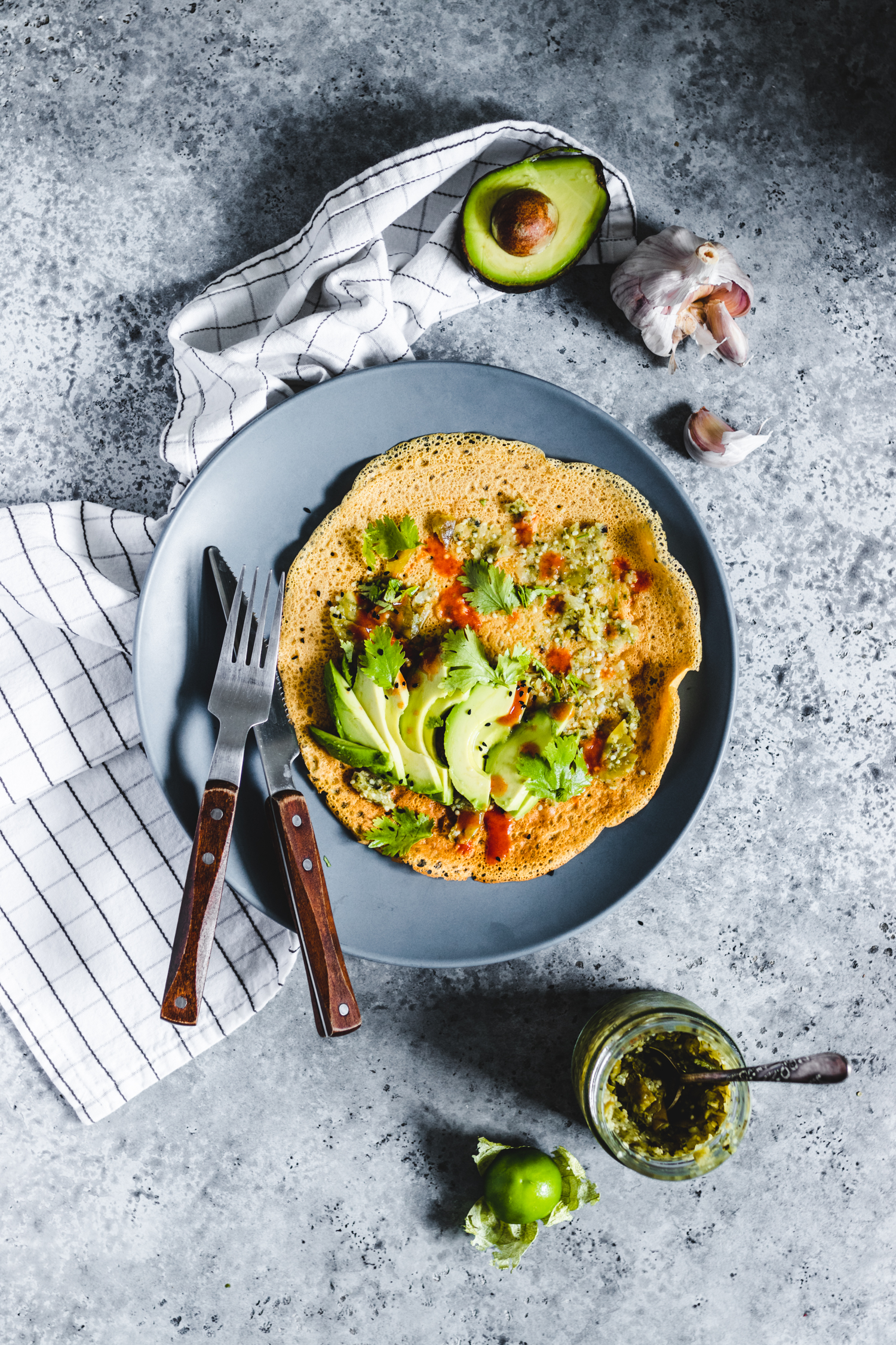 Savoury Flour Chickpea Crepes served with herbs, avocado, and hot sauce