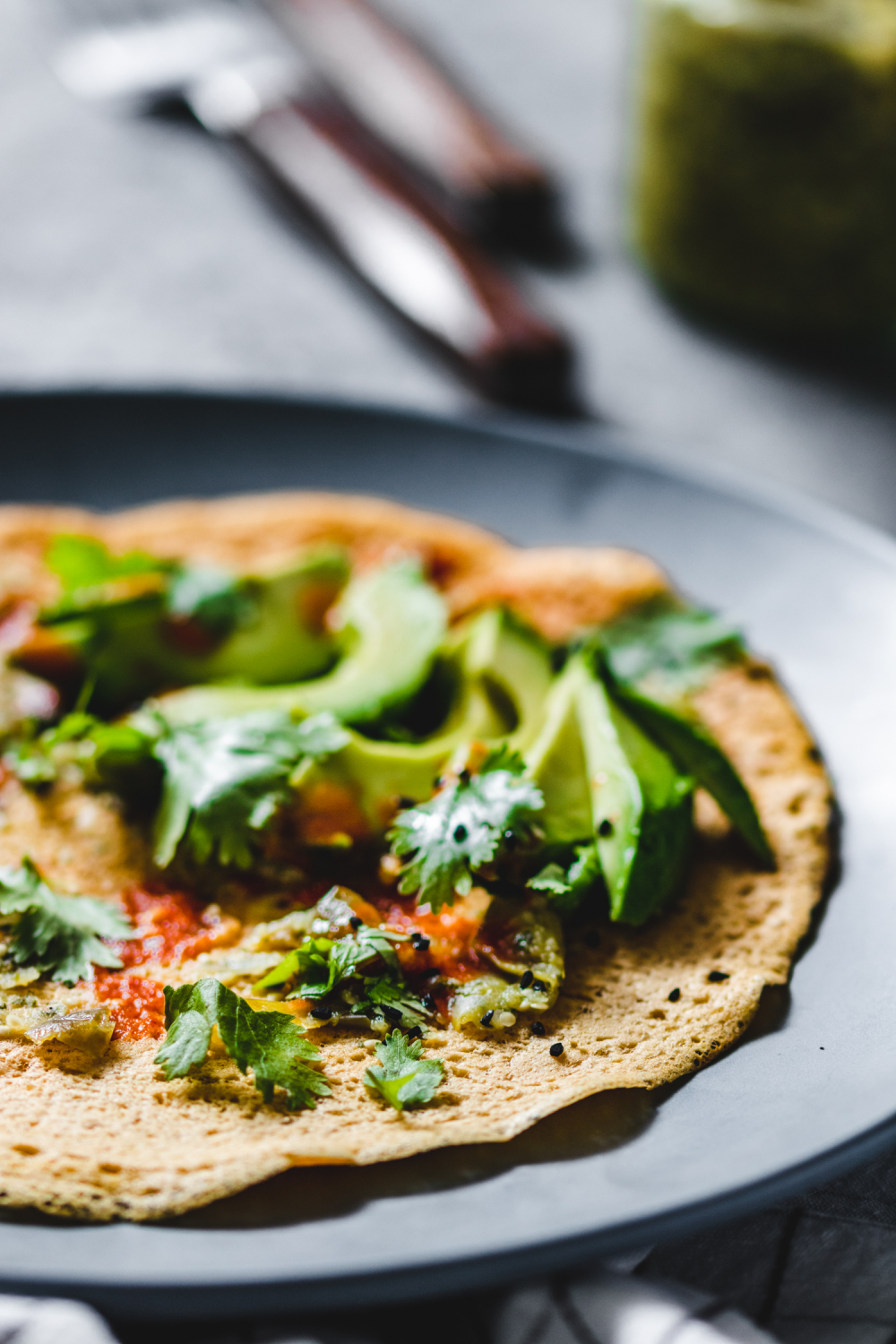 Savoury Flour Chickpea Crepes served with herbs, avocado, and hot sauce