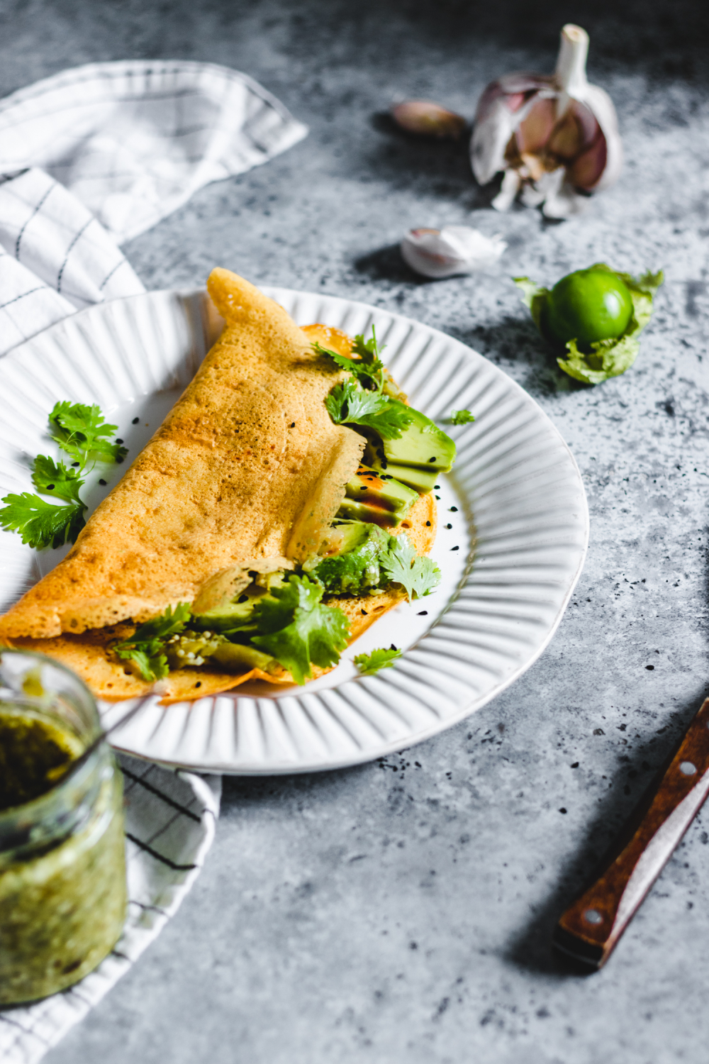 Savoury Flour Chickpea Crepes served with herbs, avocado, and hot sauce