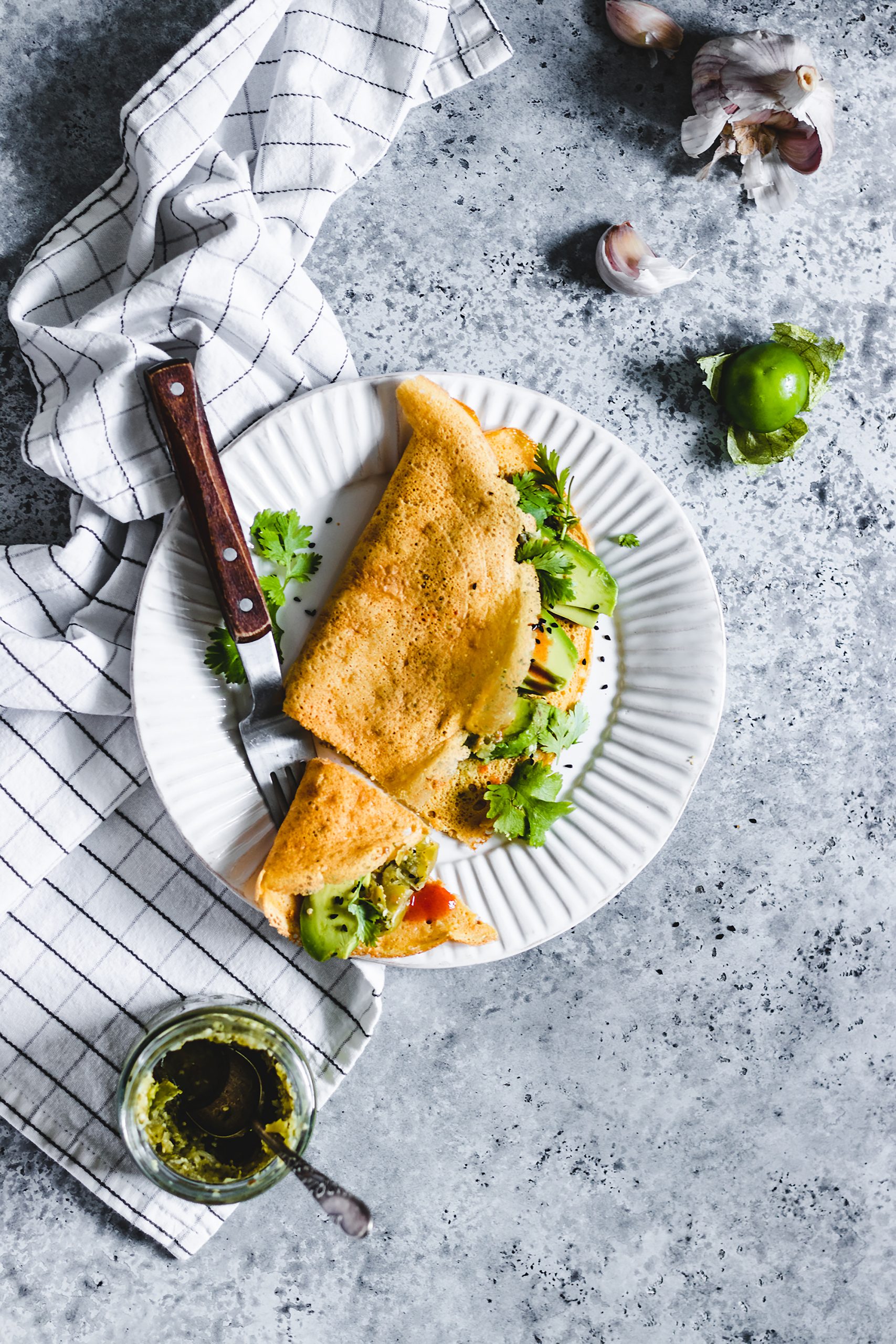 Savoury Flour Chickpea Crepes served with herbs, avocado, and hot sauce