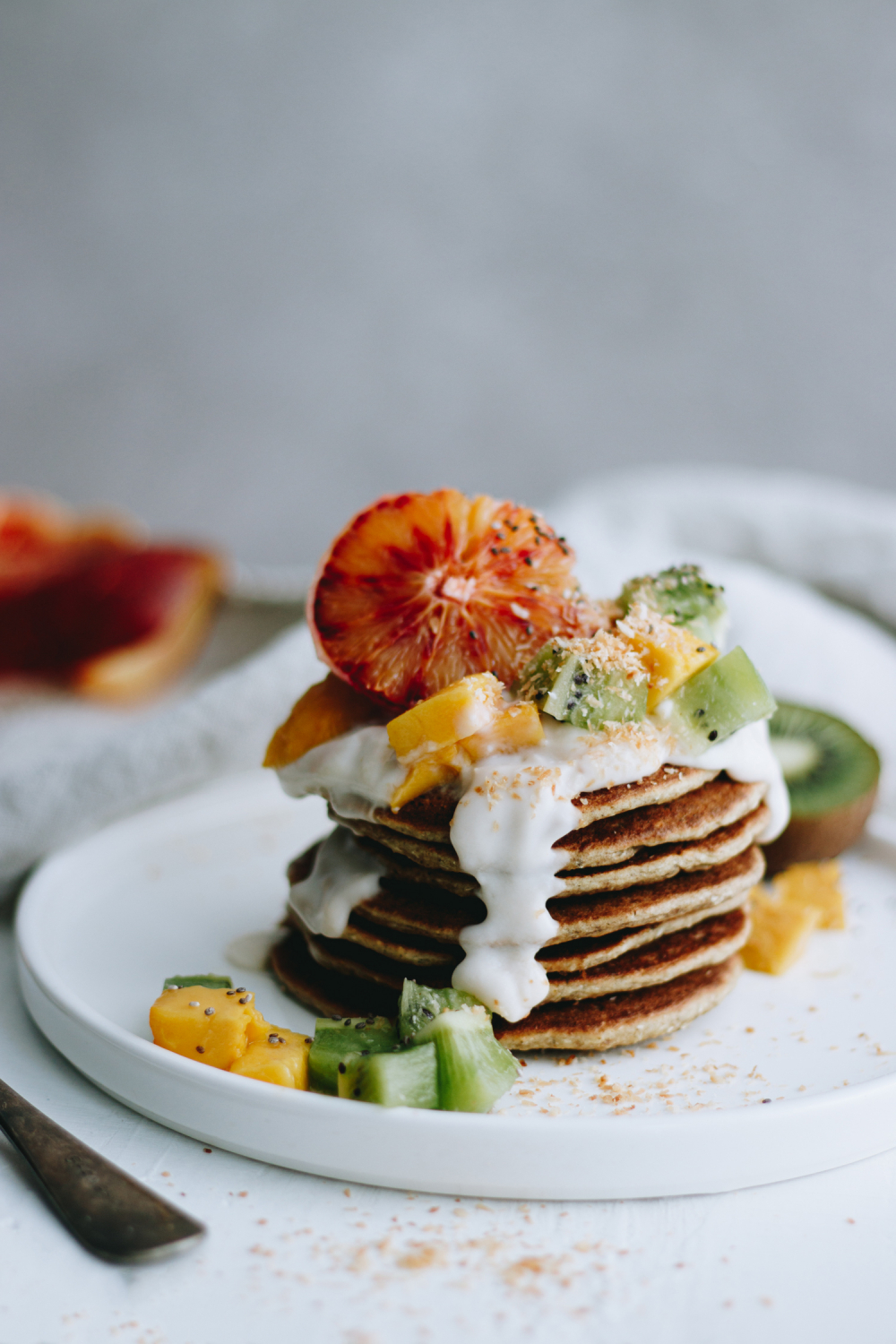 Tropical pancake stack garnished with kiwi, oranges and mangoes