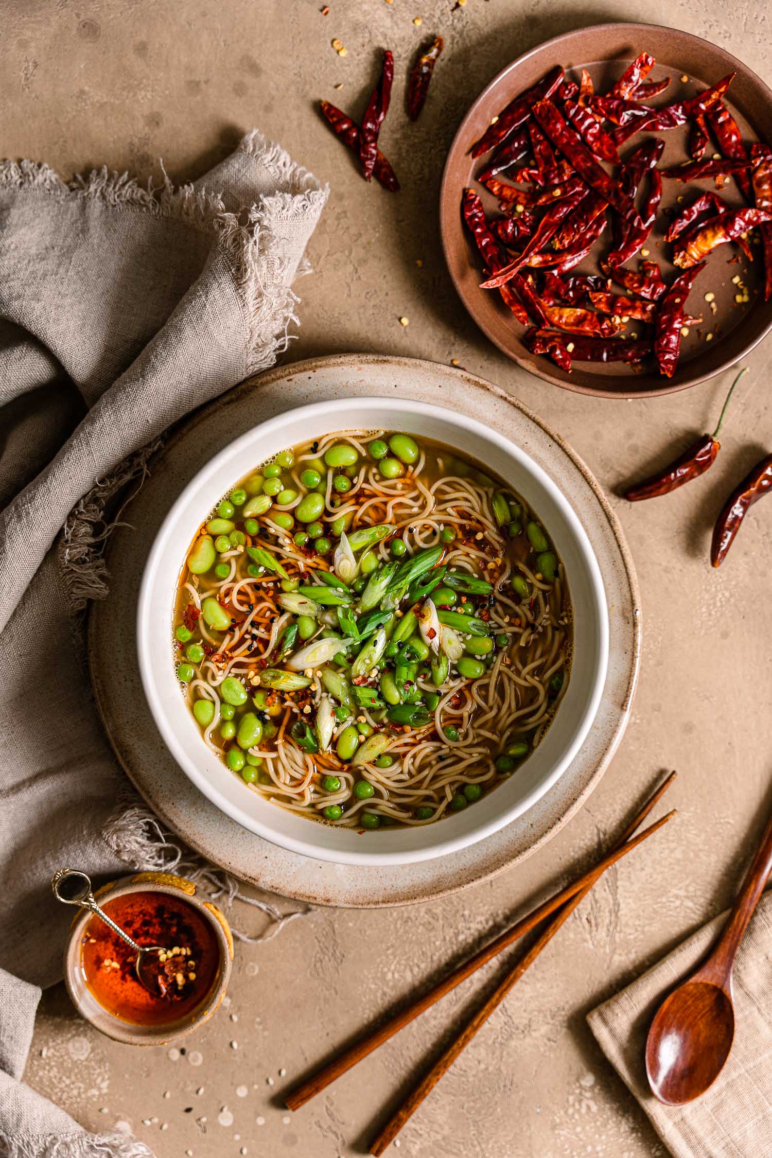 Overhead One Pot Green Ramen for One surrounded by dried red chilies, chili oil, and chopsticks