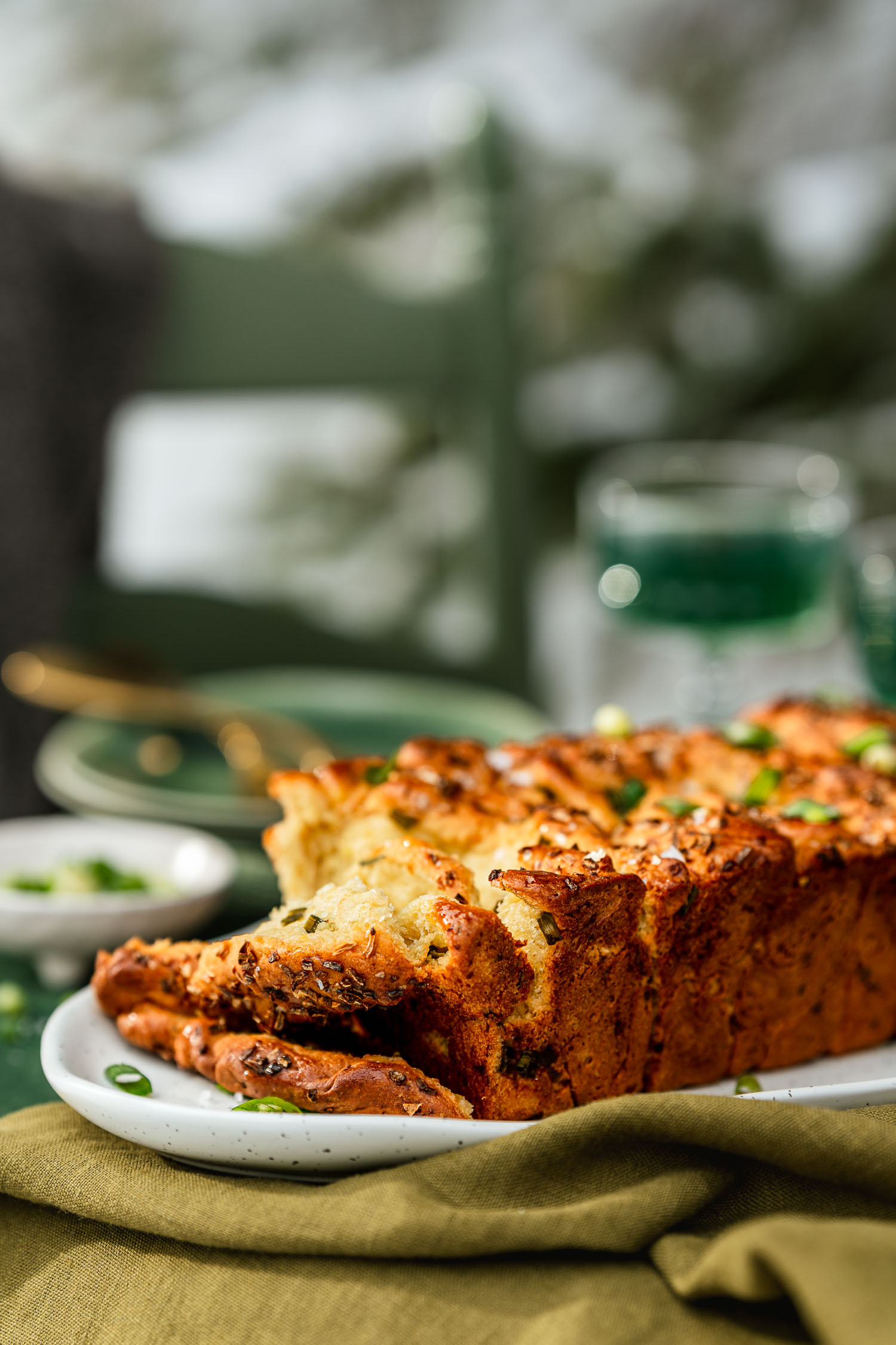 Spring Onion Pull Apart Bread set on a table, surrounded by kombucha and nature.