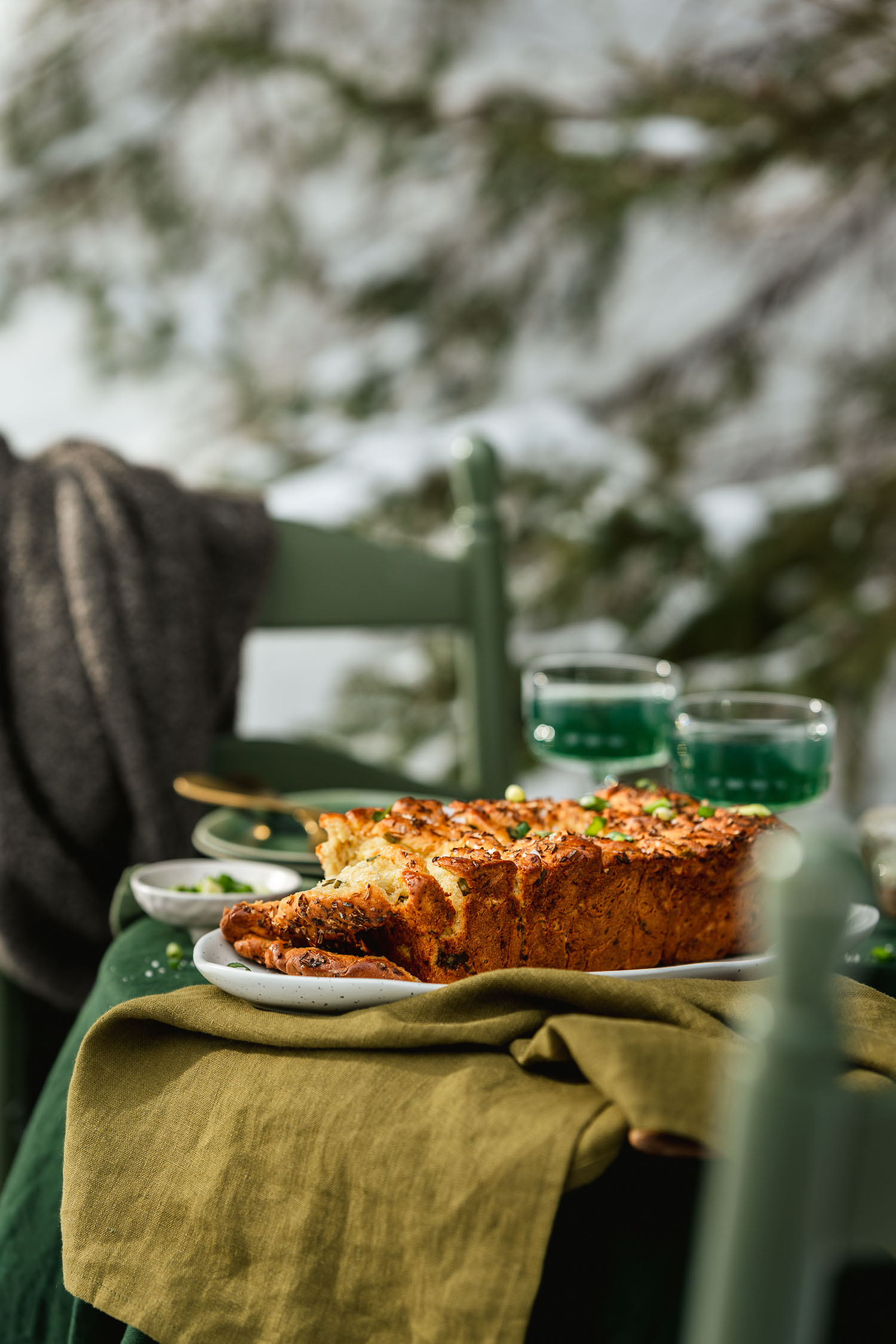 Spring Onion Pull Apart Bread set on a table, surrounded by kombucha and nature.