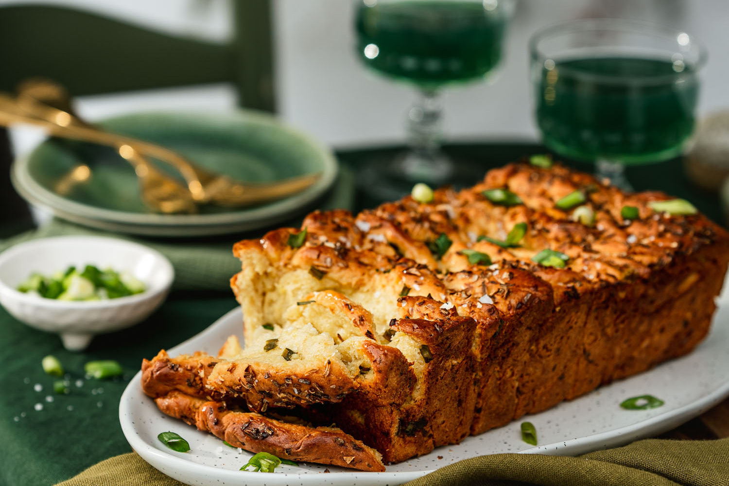 Spring Onion Pull Apart Bread set on a table, surrounded by kombucha and nature.