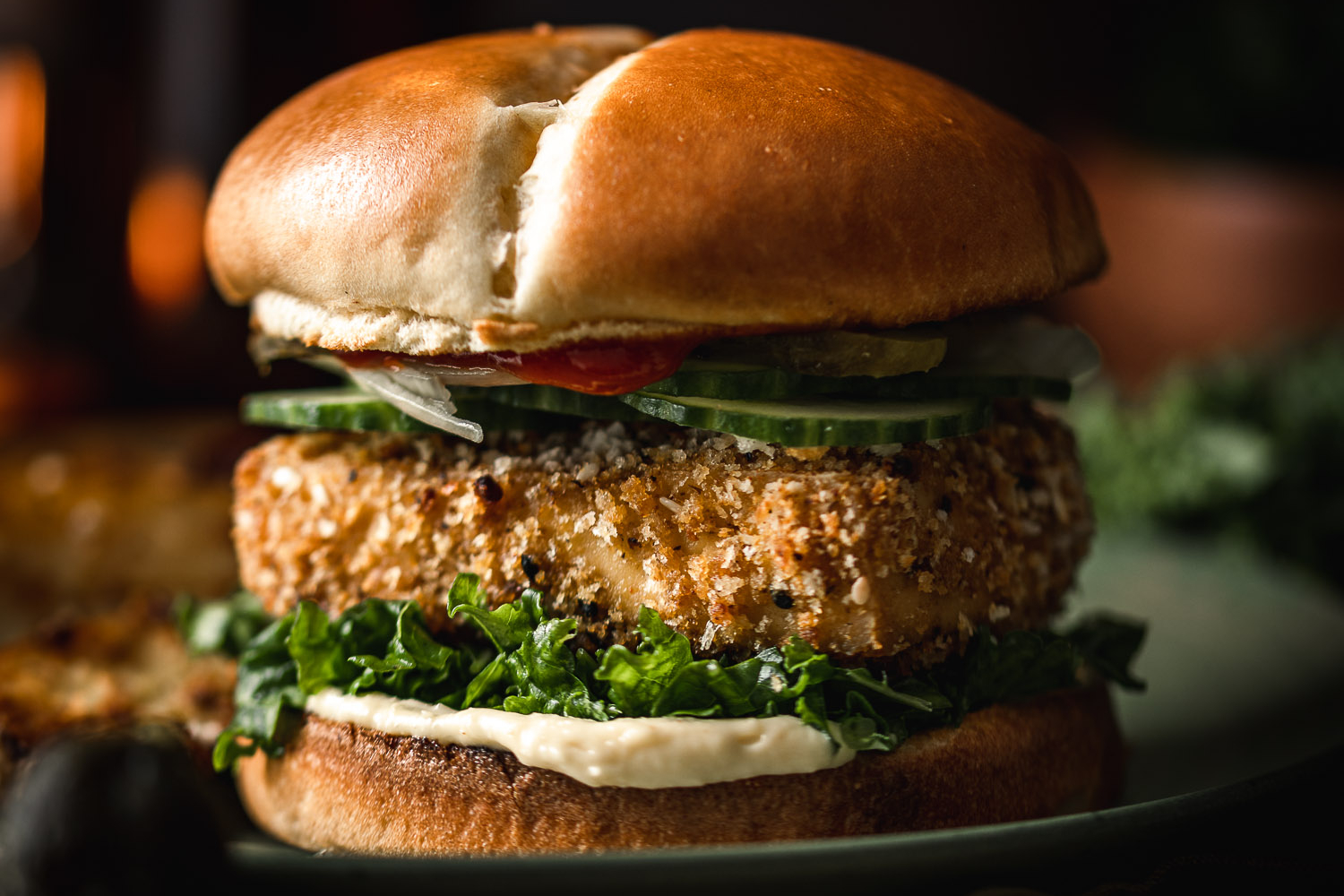 Panko Crusted Tofu Burger with Truffle Massaged Kale on a plate with candlelight in the background