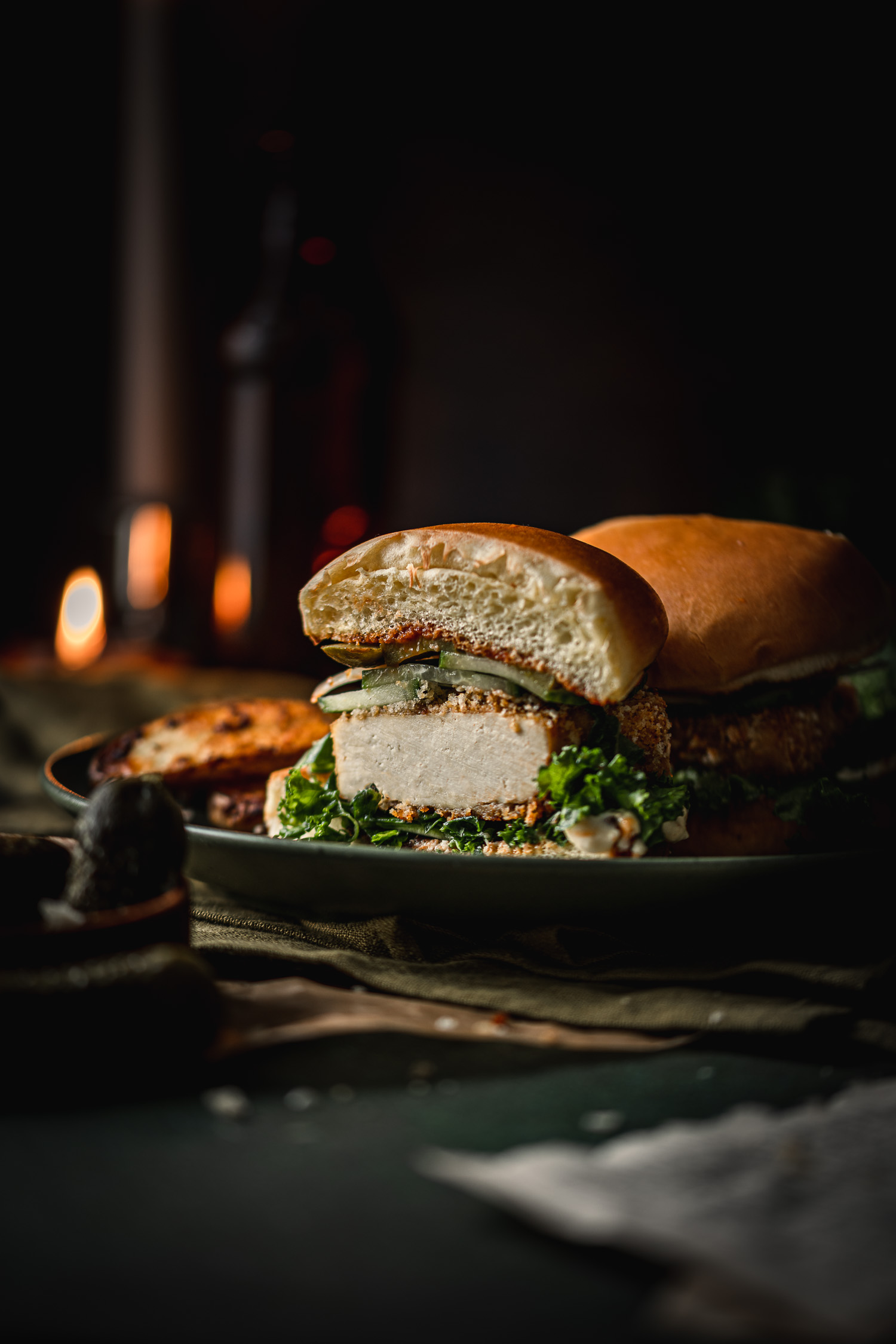Panko Crusted Tofu Burger with Truffle Massaged Kale cut in two set on a plate