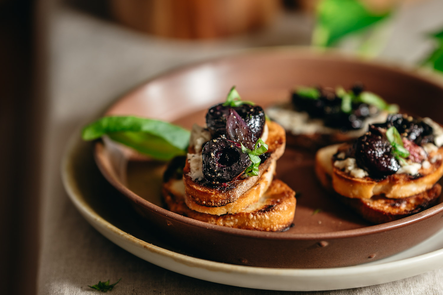 Grilled baguette topped with vegan cheese, roasted cherries, basil, and pepper