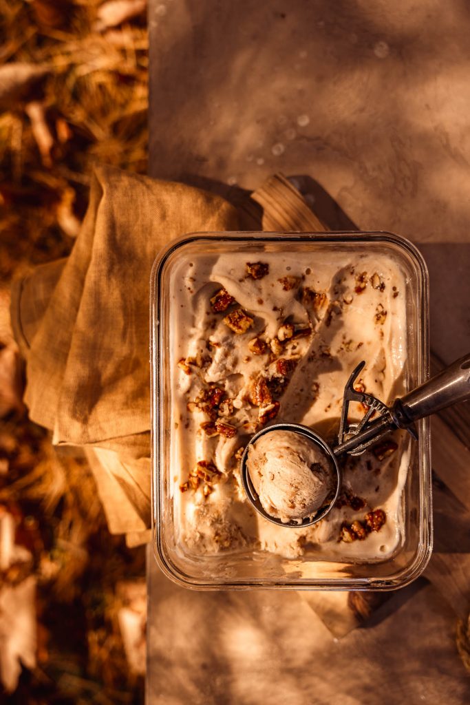 Tub of homemade Vegan Maple Pecan Ice Cream with a scoop taken out