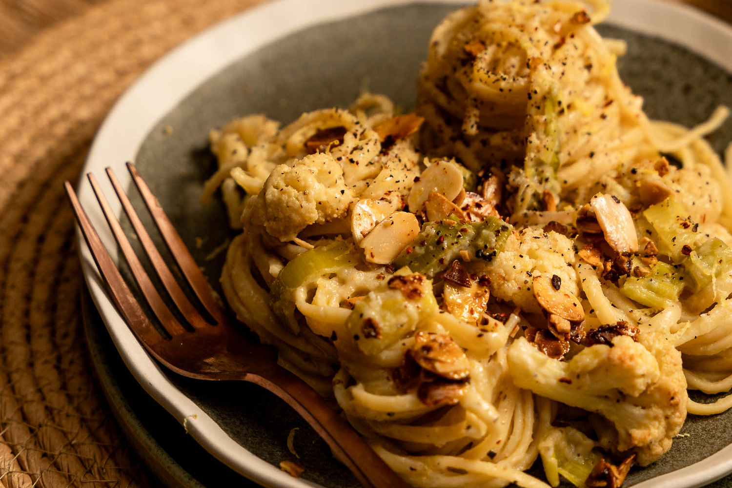 Creamy Leek and Cauliflower Linguini on a green plate topped with slivered almonds