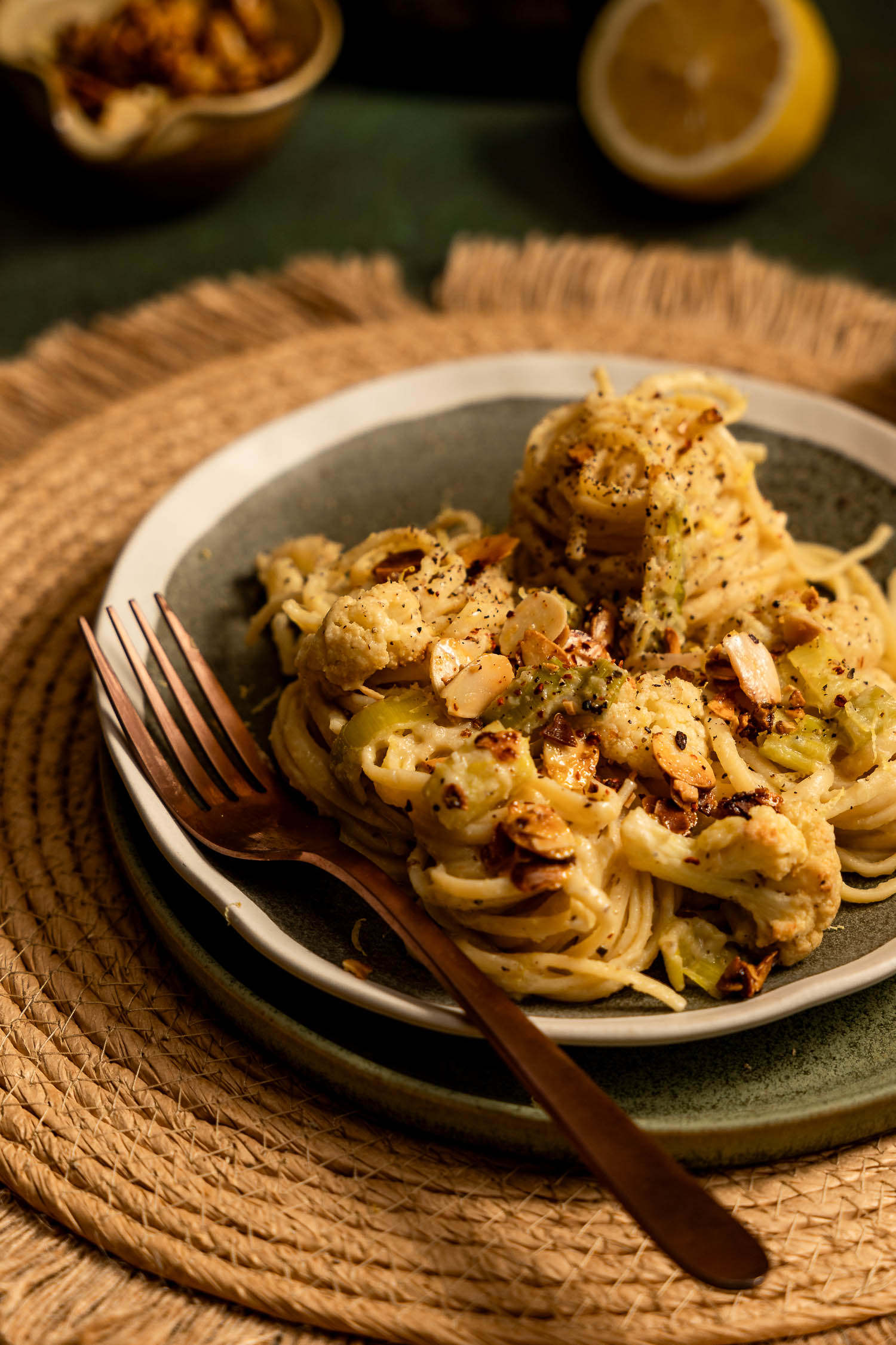 Creamy Leek and Cauliflower Linguini on a green plate topped with slivered almonds