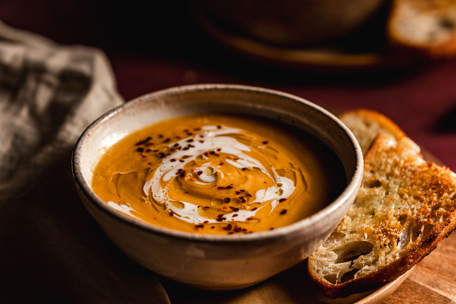 Smokey Butternut Squash Soup in a bowl with a cream and olive oil drizzle on top